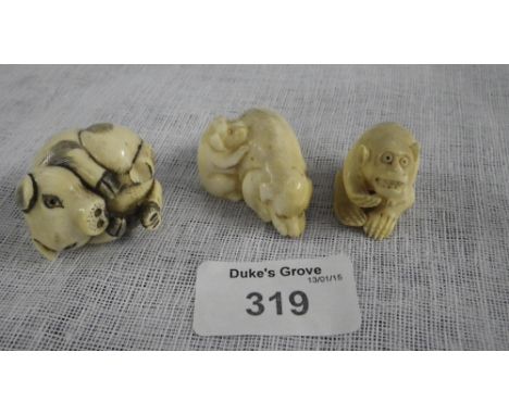 A carved ivory netsuke in the form of a small pig and two similar items