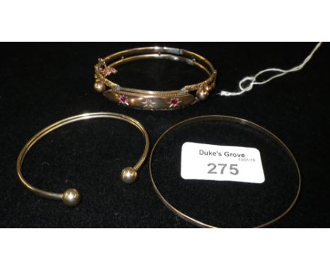 A 9ct yellow gold bangle inset with two rubies and a diamond and two other gold bangles (3)