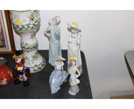 A Lladro porcelain figurine (chip to finger) together with three Nao examples.