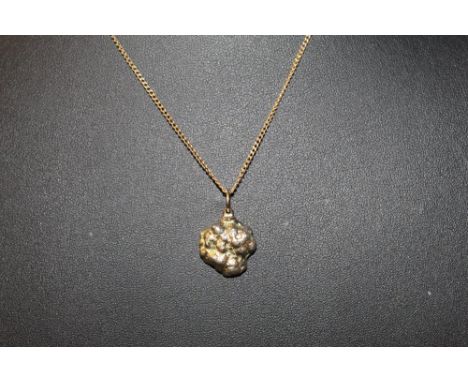 A gold coloured metal mounted blue hardstone nugget pendant, possibly sapphire, 1.5 cm high with coloured metal chain.