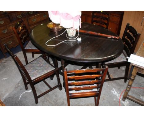 A dark elm oval gate leg table of Ercol design, 75 cm high x 150 cm long x 140 cm wide and a set of six dark wood ladder back