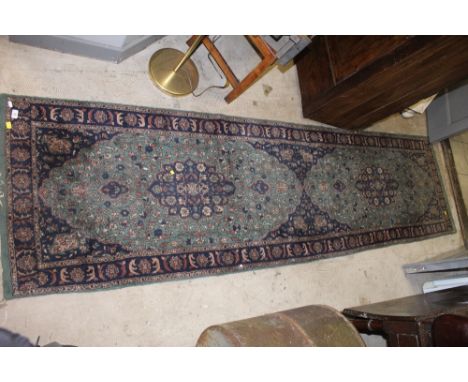 A Pakistani runner of Persian design, woven in blue and muted colours with medallions on a green ground.  294 cm long, 78 cm 