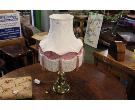A modern brass effect table lamp with tasselled shade 