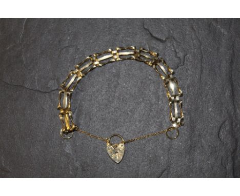 A yellow metal 3 bar gate bracelet with heart shaped padlock clasp and safety chain, unmarked, 10 grams