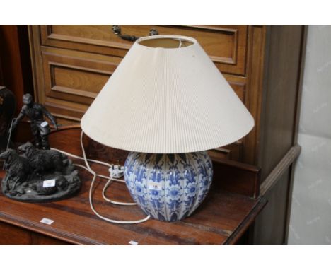 An Oriental blue and white pottery electric table lamp, the lobed body decorated with flowers, with shade. 50 cm high.