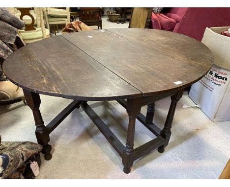 A George III oak drop-leaf dining table, the drop leaf sides form oval surface when open, supported by turned gate-legs on pa