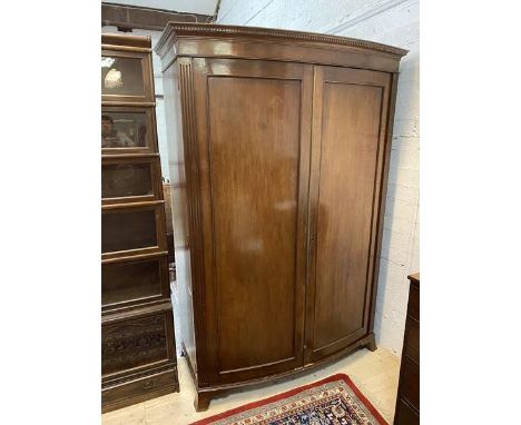 A 19thc mahogany bow front wardrobe with dentil cornice over panelled doors before single shelf and hanging space, on bracket