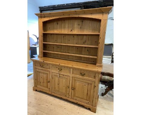 A modern pine dresser, the plate rack with three shelves within pilaster supports and moulded cornice, over three short drawe