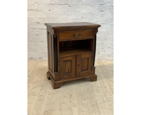 A French Empire style mahogany side cabinet, the moulded top over drawer, open shelf, and cupboard, flanked by ebonised pilas