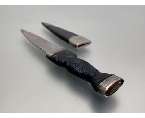 An early 20thc boy's sgian dubh, glass stone in engraved mount, carved ebony handle, steel blade and leather scabbard with en