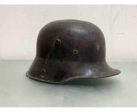 A WWI German Stalhelm M16 steel helmet with faded and worn camouflage paint, no liner or chinstrap