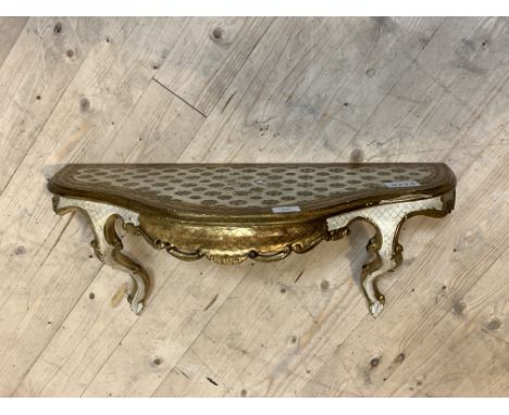 A gilt wood and cream painted Rococo style wall bracket, the top of undulating form over and shaped apron and scrolled suppor