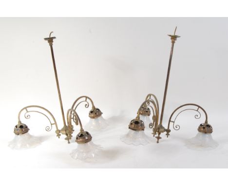 A pair of Art Nouveau brass hanging three light electroliers, each having arched scroll arms to floral domed holders, with sh