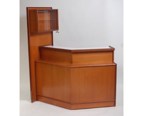 A 1970s English teak bar by Turnidge, of angular form, having white laminate inset top surface, the panelled end with twin gl