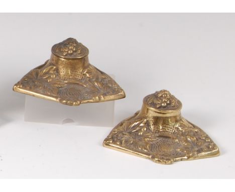 A pair of Art Nouveau cast brass lidded inkwells, each of shaped form with raised and floral stylised decoration, each enclos