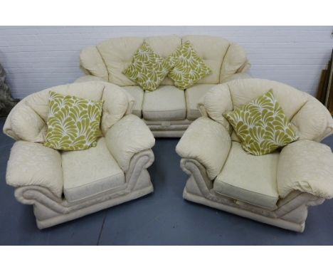 A contemporary three piece suite comprising of a three seater sofa and two easy chairs upholstered in a cream floral fabric c