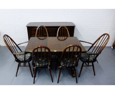 A stained Ercol drawer leaf dining table and six chairs to include two carvers together with matching sideboard (a lot) 