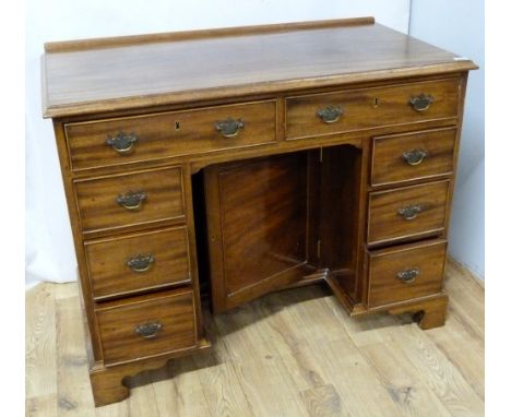 20th century mahogany writing desk in the George III style, two frieze drawers above kneehole cupboard, flanked by three draw