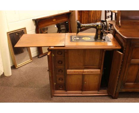 Vintage Singer cabinet sewing machine fitted with drawers containing sewing accessories.