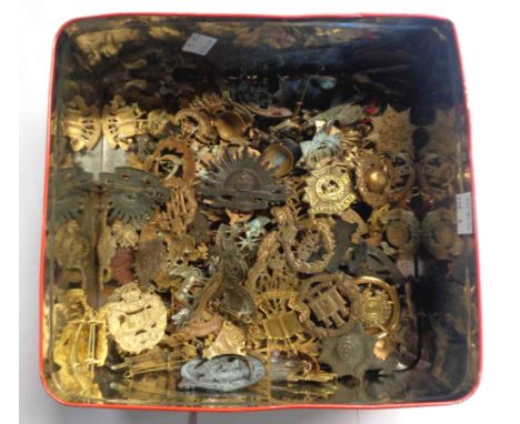 A tin containing a large collection of military and other service cotter pin back cap badges including Army Ordnance Corps, T