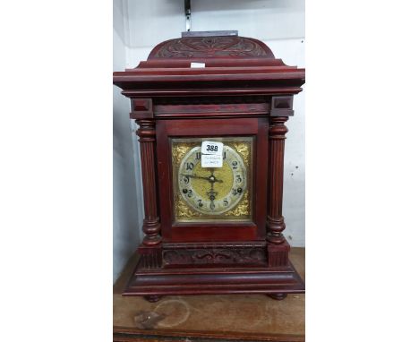 An early 20th Century German stained and carved walnut cased table clock with brass and silvered dial, scroll decoration and 