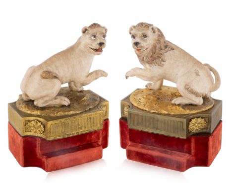 A PAIR OF CERAMIC AND BRASS LION BOOKENDS, EARLY 20TH CENTURY  each bookend formed as a lion and lioness, each with a paw up 