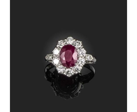 A ruby and diamond ring, of cluster design, set with an oval ruby weighing approximately 2.20 carats, within a border of bril