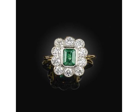 An emerald and diamond ring, of cluster design, set with a step-cut emerald weighing approximately 1.35 carats, within a bord