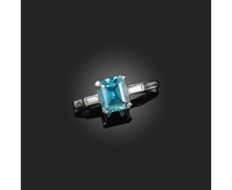 A zircon and diamond ring, claw-set with a step-cut blue zircon weighing approximately 2.00 carats, between shoulders set wit