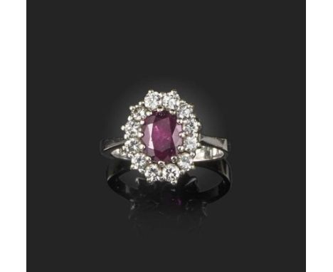 A ruby and diamond ring, of cluster design, claw-set with an oval ruby weighing approximately 0.80 carats, within a border of