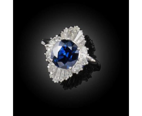 A sapphire and diamond ring, claw-set with a cushion-shaped sapphire, within a border of oval and tapered baguette diamonds, 