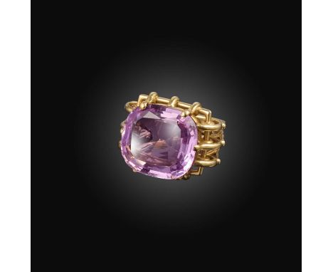 A pink topaz ring, mid 20th century, the cushion-shaped pink topaz weighing 27.06 carats, claw-set in an openwork yellow gold