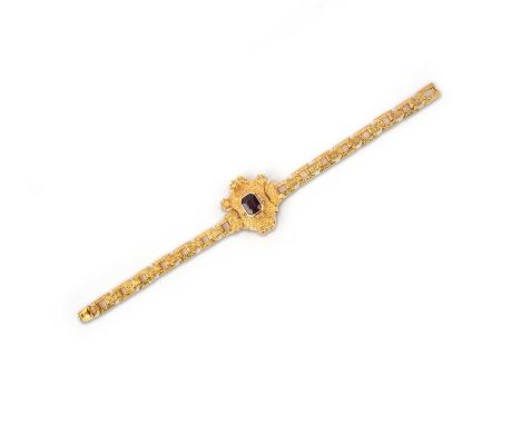 A gold and garnet bracelet, mid 19th century, centring on a step-cut almandine garnet, within an engraved shield-shaped mount