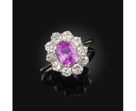 A pink sapphire and diamond ring, mid 20th century, of cluster design, set with an elongated cushion-shaped pink sapphire wei