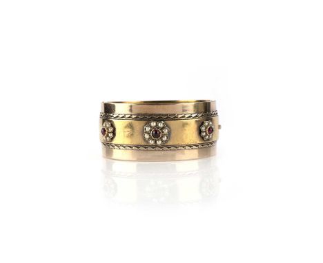 A gold, garnet and seed pearl bangle, late 19th century, the cuff of hinged construction, the front with three clusters of ca