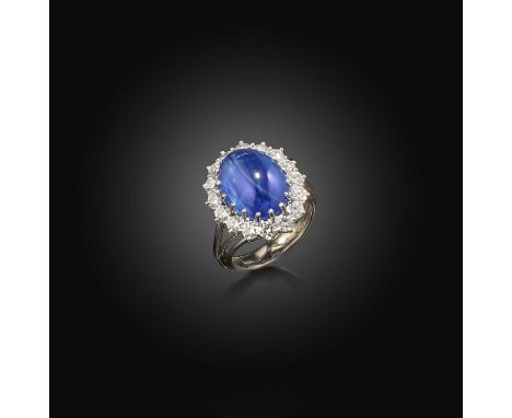 A cabochon sapphire and diamond cluster ring, the oval cabochon sapphire weighing 14.5cts, set within a surround of circular-