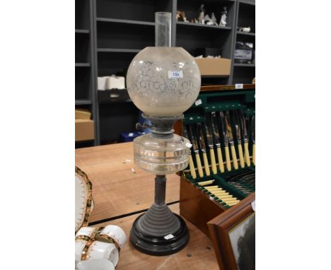 An early 20th century oil lamp, having etched glass shade, clear reservoir and copper column mounted on ceramic base.