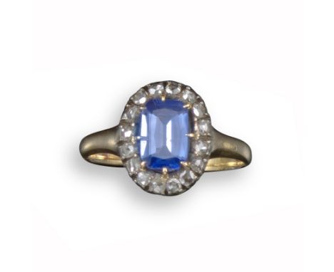 A sapphire and diamond cluster ring, the step-cut sapphire is set within a surround of rose-cut diamonds in silver and gold, 