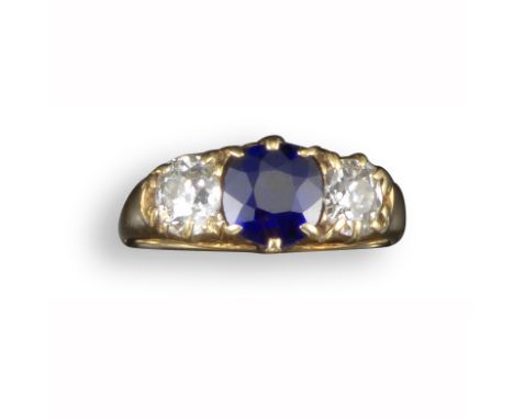 A late 19th century sapphire and diamond three-stone ring, the cushion-shaped sapphire flanked with old circular-cut diamonds