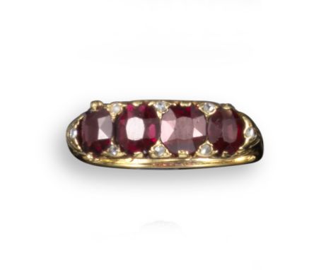 A late 19th century garnet and diamond four stone ring, the four garnets set with diamond pointers in carved and pierced yell