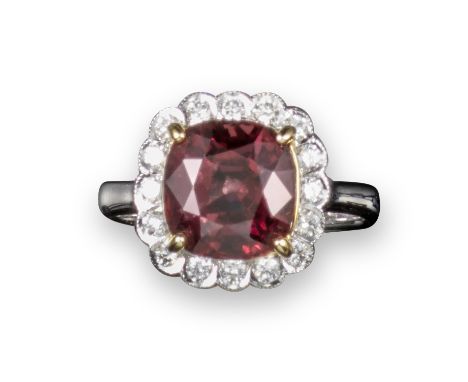 A spinel and diamond cluster ring, the cushion-shaped red spinel is set within a surround of circular-cut diamonds in yellow 