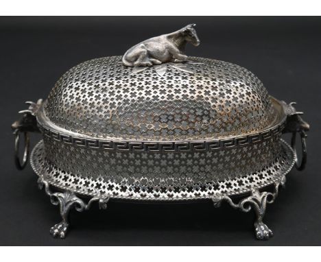A late 19th century silver plated pierced and lidded butter dish with glass liner and cow shaped finial with twin bull mask h
