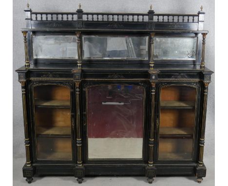 A late Victorian ebonised mirror backed credenza with allover incised gilt carving the bevelled doors flanked by fluted pilas