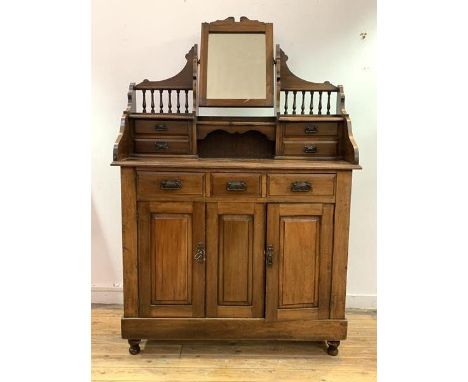 An early 20th century walnut dressing chest, the top fitted with swing mirror and trinket drawers over three drawers and two 