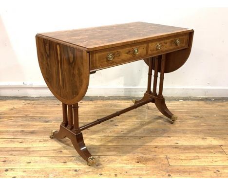 A figured walnut and yew wood sofa table of Regency design, the cross banded top with two drop leaves over two drawers opposi