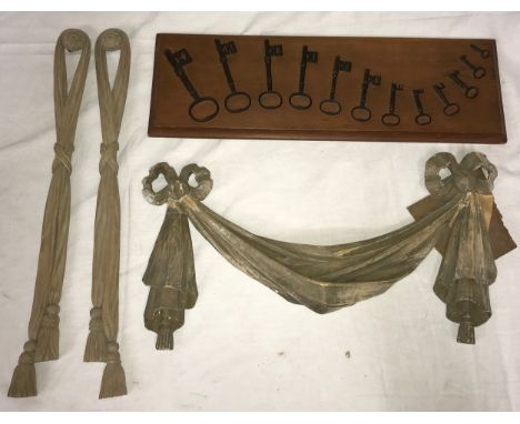 A pair of tasselled wooden carved wall hangings in a ribbon design 53.5cm h x 5.5cm w along with a wooden carved curved wall 