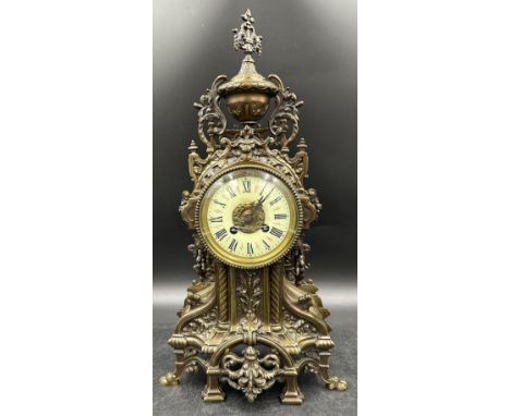 A large ornate brass mantle clock with white enamel face. 49cm h.