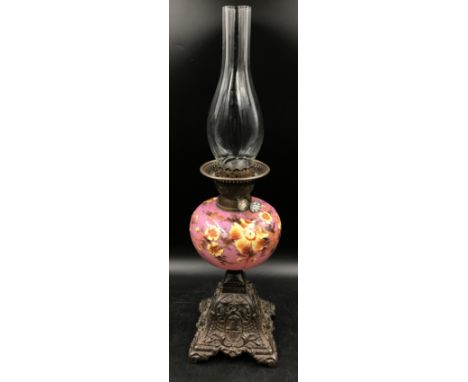 An oil lamp decorated in hand painted yellow flowers on a pink background marked Duplex with clear glass chimney 61cm h. 