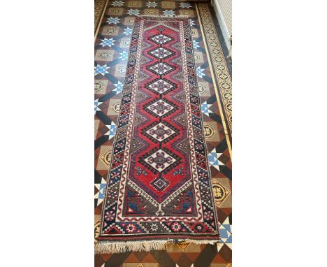 A vintage wool carpet runner in shades of red. 288 l x 82cm w without tassels. 