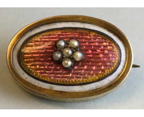 A small oval memorial brooch with rose engine turned enamel with a foliate setting of six seed pearls, border of white enamel